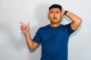 Mavi tişörtlü genç Asyalı kafası karışmış bir yüzü olan bir adamı işaret ediyor.