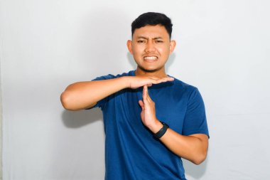 Mavi tişörtlü genç Asyalı adam jest yapıyor.