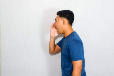 Mavi tişörtlü genç Asyalı bağırarak jest yapıyor.