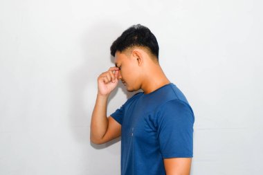 Asyalı mavi tişörtlü genç adam düşünme jesti yapıyor.