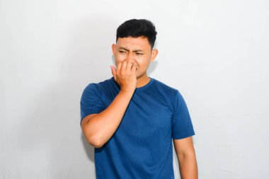 Asyalı mavi tişörtlü genç adam korkmuş bir ifadeyle parmağını ısırıyor.