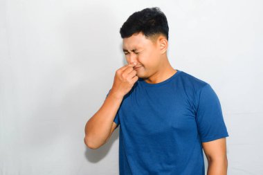 Çöp kokusu yüzünden mavi tişörtlü genç Asyalı burnu kapatıyor.