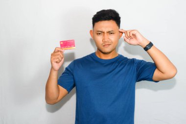 Mavi gömlekli genç Asyalı adam kredi kartı gösteriyor ve işaret ediyor.