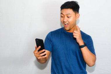 Dost canlısı genç Endonezyalı bir adam mavi tişört giyiyor, elinde 