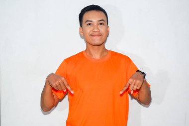 Dost canlısı, turuncu tişörtlü, işaret parmağıyla aşağıya bakan Asyalı bir adam.