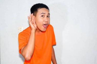 Dost canlısı, turuncu tişört giyen Asyalı adam dinleme hareketi yapıyor.