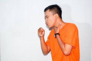 Dost canlısı Asyalı adam turuncu tişört giyiyor boğaz ağrısı ya da öksürük