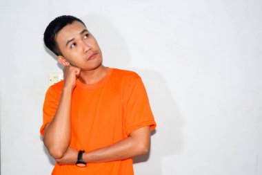 Dost canlısı Asyalı adam turuncu tişört giyiyor.