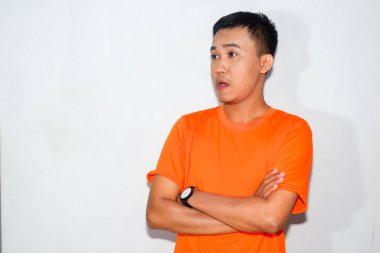 Kollarını kavuşturmuş turuncu tişört giyen dost canlısı Asyalı adam.