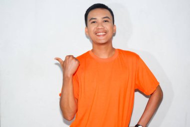 Dost canlısı, turuncu tişörtlü Asyalı adam başparmağıyla yan tarafı gösteriyor.