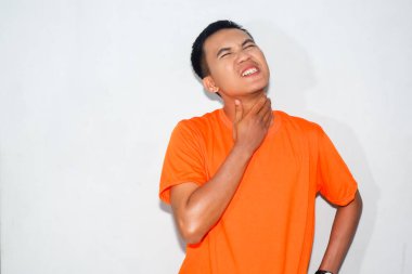 Dost canlısı Asyalı adam boğazı ağrıyan turuncu tişört giyiyor.