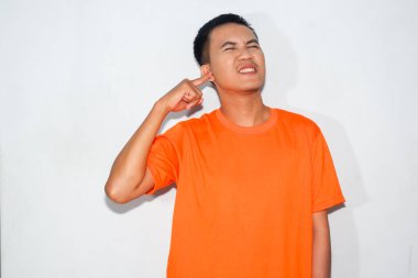 Turuncu tişört giyen dost canlısı Asyalı adamın kulak ağrısı var.