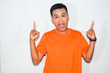 Dost canlısı, turuncu tişörtlü, yüzünde iki parmağıyla işaret eden Asyalı adam.
