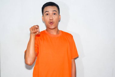 Dost canlısı Asyalı adam turuncu tişört giyiyor ve yüzünde komik bir ifade var.