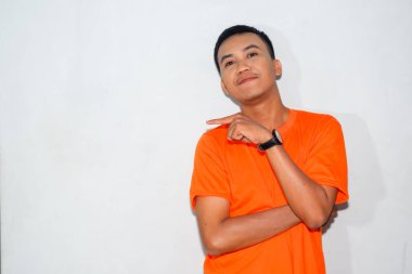 Dost canlısı Asyalı adam turuncu tişört giyiyor ve gülümsüyor.