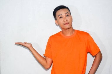 Turuncu tişört giyen hevesli Asyalı bir adam, dostane bir ifadeyle ürünü gösteren bir jest yapıyor..