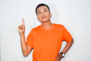 Dost canlısı Asyalı adam turuncu tişört giyiyor ve gülümsüyor.