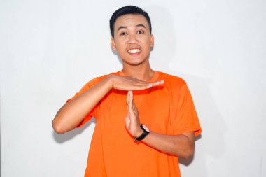 Heyecanlı, turuncu tişörtlü, paniklemiş bir Asyalı adam.