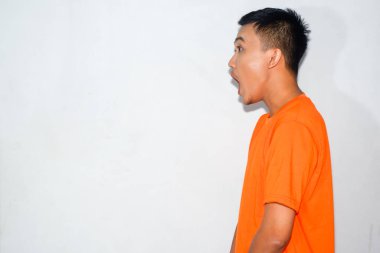 Heyecanlı Asyalı adam turuncu tişört giyiyor.