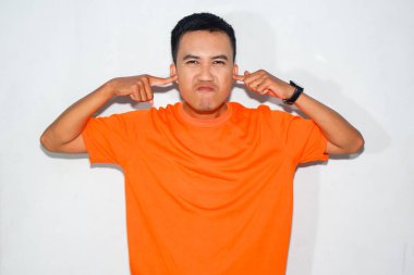 Heyecanlı, turuncu tişörtlü, sinirli bir Asyalı, kulaklarını kapatmak için harekete geçiyor.