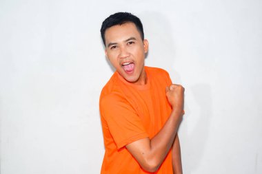 Heyecanlı Asyalı adam turuncu tişört giyiyor ve mutlu bir ifade takınıyor.