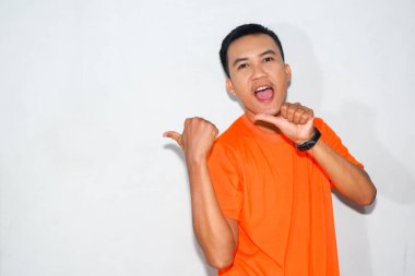 Turuncu tişört giyen heyecanlı bir Asyalı adam iki başparmağıyla bir jest yapıyor.