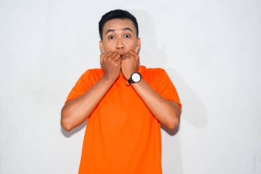 Heyecanlı, turuncu tişörtlü, korkmuş bir Asyalı parmak ısırma hareketi yapıyor.