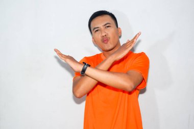 Ciddi bir ifadeye sahip turuncu tişört giyen hevesli Asyalı bir adam reddediyor ya da yasaklıyor..