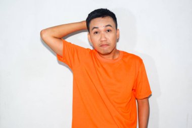 Heyecanlı Asyalı adam turuncu tişört giyiyor ve komik bir ifade takınıyor.