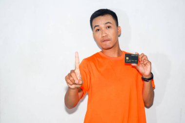 Turuncu tişörtlü Asyalı adam kredi kartı gösteriyor ve içki yasağı hareketi yapıyor.