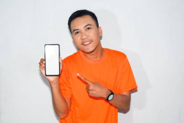 Turuncu tişört giyen Asyalı bir adam beyaz akıllı telefon ekranını işaret ediyor.