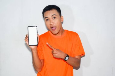 Turuncu tişört giyen Asyalı bir adam beyaz akıllı telefon ekranını işaret ediyor.
