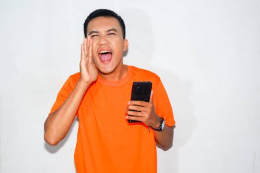 Dost canlısı, turuncu tişörtlü, akıllı telefon tutan ve bağıran Asyalı bir adam. Heyecan, iletişim ya da duygularını ifade etme kavramı