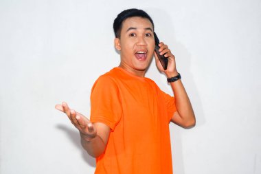 Dost canlısı, turuncu tişörtlü, telefonda konuşan ve hoş geldin jesti yapan Asyalı bir adam. Selamlama, iletişim ya da sıcaklığı ifade etme kavramı