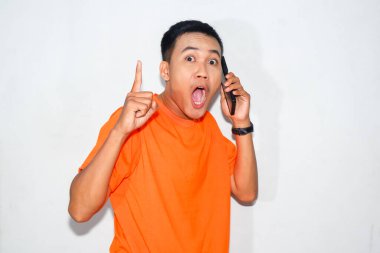 Turuncu tişörtlü Asyalı adam diye bağırmak, telefonda konuşmak ve yukarıya doğru işaret etmek. Heyecan kavramı, vurgu, ya da bir telefon konuşması sırasında coşku ifade etmek.