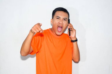 Turuncu tişört giymiş Asyalı bir adam bağırıyor, telefonda konuşuyor ve ileri işaret ediyor. Bir telefon konuşması sırasında heyecan, vurgu ya da güçlü tepki kavramı