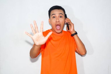 Turuncu tişört giyen Asyalı adam diye bağırmak, telefonda konuşmak ve reddetme hareketi yapmak. Bir telefon görüşmesi sırasında anlaşmazlık, uyarı veya güçlü tepki kavramı