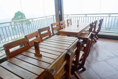 Ahşap masa ve sandalyeler cam pencerelerden manzaralı dağ manzaralı bir kafede düzgünce düzenlenmiş.