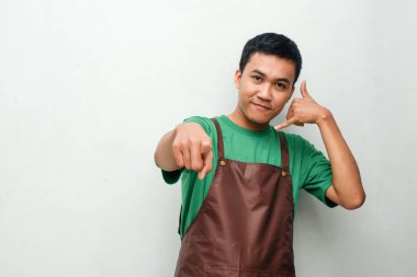Yeşil tişörtlü ve kahverengi önlüklü genç adam bana iyi niyet göstergesi olarak hitap ediyor.