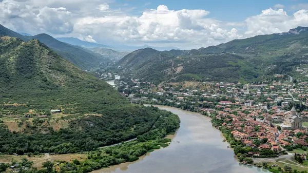 Aragvi ve Mtkvari nehirlerinin birleştiği Gürcistan 'ın Mtskheta kentinin nefes kesici manzarası. Verimli yeşil tepeler, kırmızı kiremitli çatılar ve ikonik Svetitskhoveli Katedrali ile tarihi kasabayı çevrelemektedir..