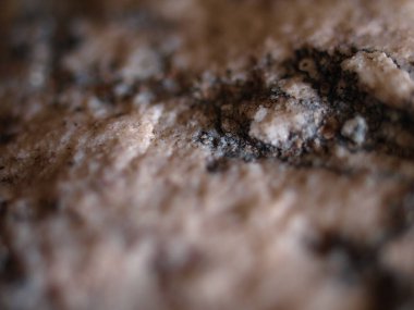 Doğal granit taşın yakın çekim dokusu, granüler detayları ışık ve koyu mineral parçacıkları karışımıyla gösteriyor.. 
