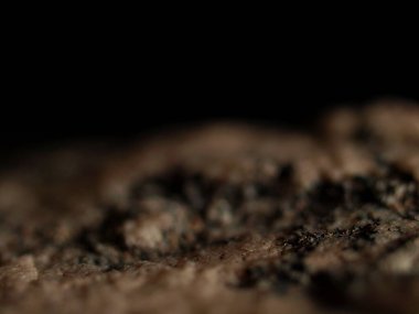 Koyu bir arka planda izole edilmiş pürüzlü granit taşın kenarına yakın plan. Görüntü karamsar, dramatik bir manzaraya sahip, sığ bir alan derinliği var..