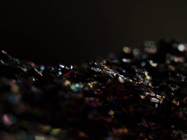 Makro karborundum şat, parlak gökkuşağı renkli kristallerini sergiliyor keskin, açısal formasyonları var. Metalik yüzey, canlı yansımalarla, kozmik bir manzarayı çağrıştırıyor..