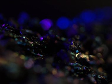 Makro karborundum şat, parlak gökkuşağı renkli kristallerini sergiliyor keskin, açısal formasyonları var. Metalik yüzey, canlı yansımalarla, kozmik bir manzarayı çağrıştırıyor..
