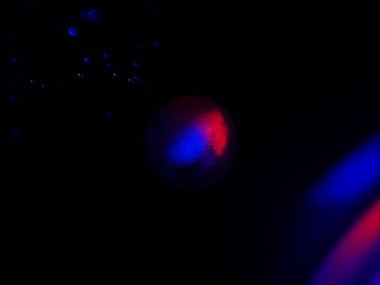 Parlayan, küresel bir nesnenin yakın plan, parlak pembe ve mavi ışıklarla kaplanmış, soyut, kozmik bir atmosfer yaratıyor..