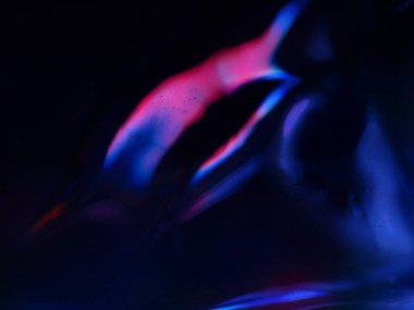 Renkli ışık yansımalarının soyut yakın çekimi. Görüntü, derinlik ve hareket hissi uyandıran canlı ve yanardöner renklere sahip koyu bir arkaplan içeriyor..