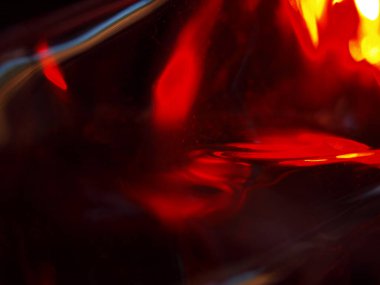 Renkli ışık yansımalarının soyut yakın çekimi. Görüntü, derinlik ve hareket hissi uyandıran canlı ve yanardöner renklere sahip koyu bir arkaplan içeriyor..