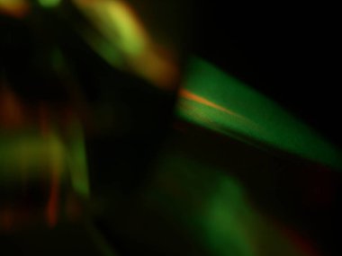 Canlı, üst üste binen renklerin soyut makro fotoğrafı koyu bir zemin üzerinde yumuşak ve ışıltılı bir etki yaratıyor. Bu renkli spektrum belirli bir hareket ve derinlik duygusunu yakalar..