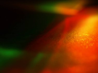 Canlı, üst üste binen renklerin soyut makro fotoğrafı koyu bir zemin üzerinde yumuşak ve ışıltılı bir etki yaratıyor. Bu renkli spektrum belirli bir hareket ve derinlik duygusunu yakalar..