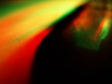 Canlı, üst üste binen renklerin soyut makro fotoğrafı koyu bir zemin üzerinde yumuşak ve ışıltılı bir etki yaratıyor. Bu renkli spektrum belirli bir hareket ve derinlik duygusunu yakalar..